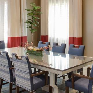 A beautifully decorated dining room with a large table, blue chairs, and elegant curtains.