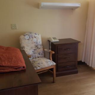 A cozy room featuring a floral chair and a wooden bedside table.