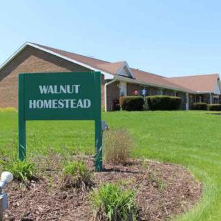 A building with a sign reading 'Walnut Homestead' in front of a well-maintained lawn.