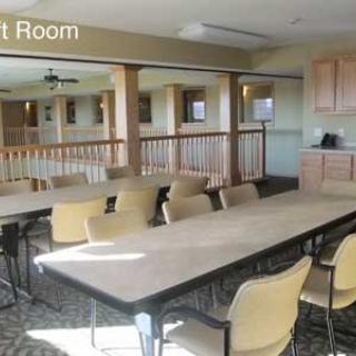 A spacious meeting room with a long conference table and several chairs, featuring natural light from windows.
