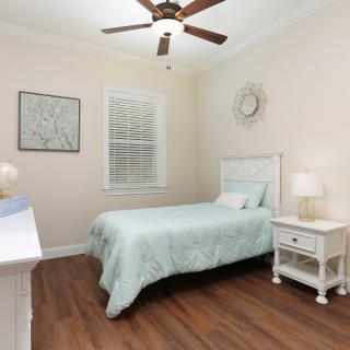 A cozy bedroom with a single bed, wooden flooring, and soft lighting.