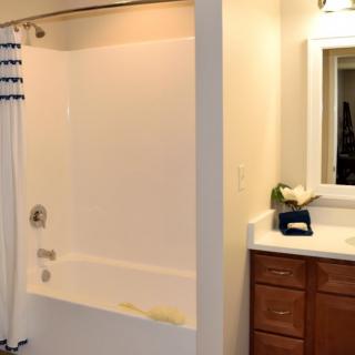 A clean and simple bathroom with a bathtub and shower curtain next to a sink and mirror.
