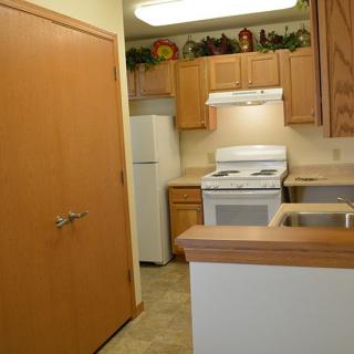 A compact kitchen with wooden cabinets, a white stove, and a refrigerator.