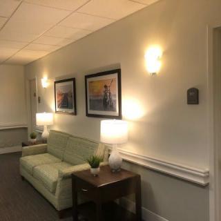 A cozy hallway with a green sofa, soft lighting, and framed artwork on the walls.