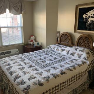 A cozy bedroom with a quilted bedspread and decorative details.