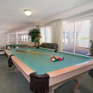 A spacious game room featuring a billiards table with cues and pool balls.