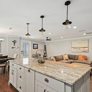 A modern open floor plan combining a kitchen and living room, featuring a large kitchen island with pendant lighting and a comfortable seating area.