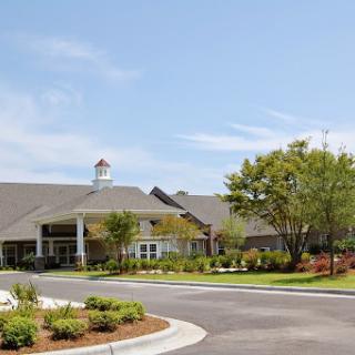 A well-designed residential building with landscaped gardens and a clear blue sky.