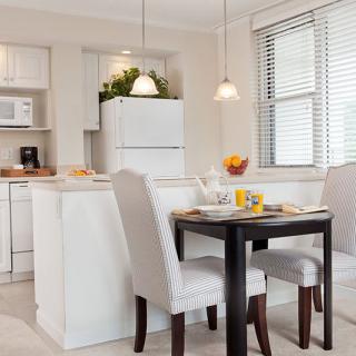 A modern kitchen and dining area with white furniture and ample natural light.