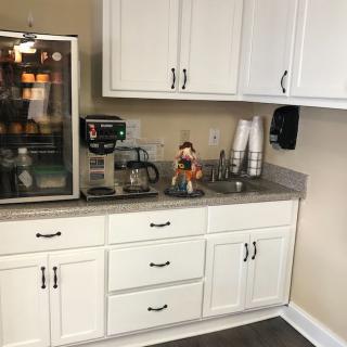 A well-organized kitchen counter with a coffee maker and cups ready for use.