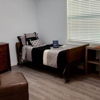 A minimalist bedroom with a single bed, desk, and dresser.