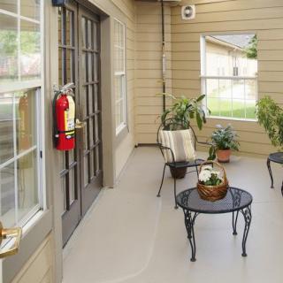 A cozy patio with a table, chairs, and plants, featuring a fire extinguisher mounted on the wall.