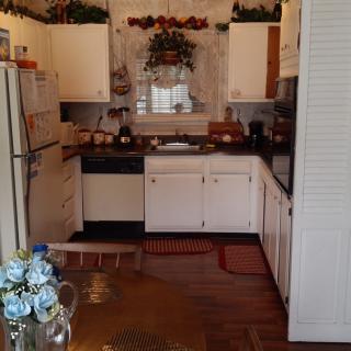 A cozy kitchen with white cabinets and floral decorations.