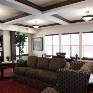 A cozy living room with a sofa, armchairs, and natural light from multiple windows.