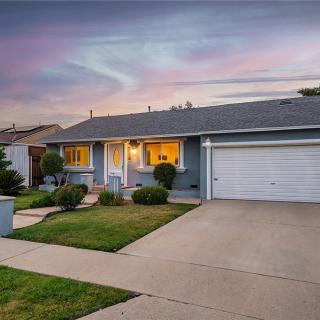 A cozy suburban house with a well-maintained lawn and driveway, illuminated at dusk.
