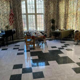A spacious room with large windows, patterned floor, and arranged furniture.