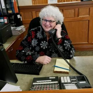 A woman sitting at a desk in an office, speaking on the phone.
