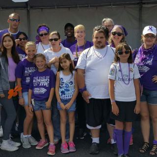 A group of people wearing purple shirts gathered outside for a community event.