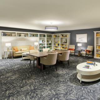 A cozy living room with comfortable seating, bookshelves, and a central table.