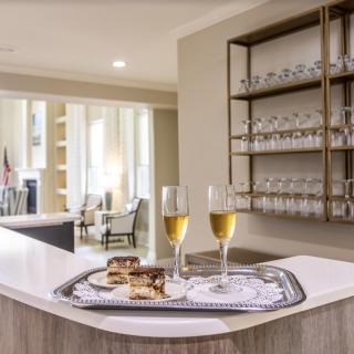 A modern lounge area featuring a countertop with two glasses of champagne on a tray, complemented by elegant shelving in the background.