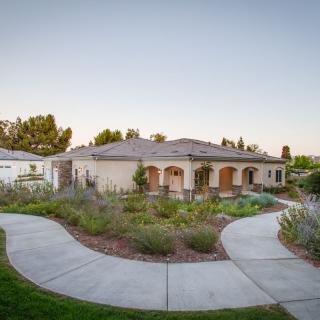 A beautiful single-story home surrounded by a landscaped garden and winding pathways.