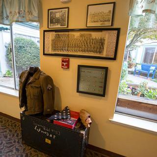 A display featuring a vintage military uniform and memorabilia, accompanied by framed historical photographs on the wall.