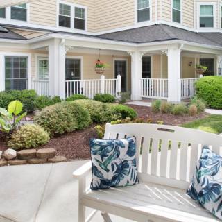 A well-maintained garden with a white bench in front of a charming house.