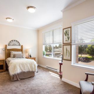 A cozy bedroom with a single bed and ample natural light from large windows.