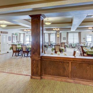 A spacious dining area featuring wooden decor, multiple tables and chairs, with ample natural light from large windows.
