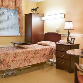 A well-furnished hospital room with a bed, lamp, and decorative elements.