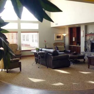 A modern living room with large windows, comfortable seating, and warm natural lighting.