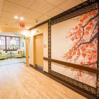 A warmly lit hallway featuring a large wall art piece with floral design, leading to a cozy seating area.