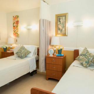A cozy bedroom with two neatly arranged beds, decorative pillows, lamps, and wall art.