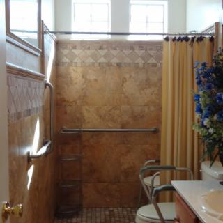 A small bathroom featuring a shower with patterned tiles, a yellow curtain, and blue floral decorations on the sink counter.