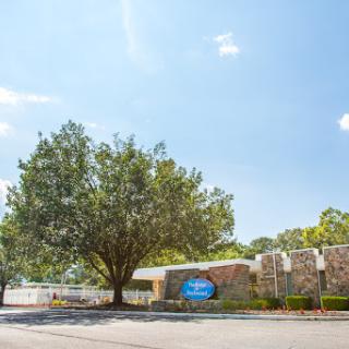A serene view of a building surrounded by lush trees and a clear blue sky.