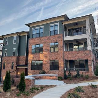 A modern apartment building with a brick facade, surrounded by landscaped pathways.