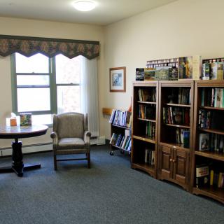 A cozy reading room with bookshelves, a chair, and a small table by the window.