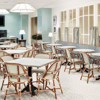 An inviting indoor cafe space with neatly arranged tables and chairs, featuring soft lighting and elegant decor.