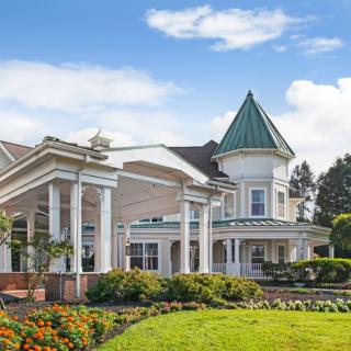 A large residential building with well-maintained landscaping and a clear blue sky.