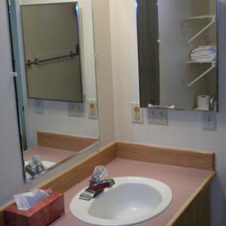 A bathroom vanity with a sink, mirror, and a tissue box.