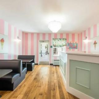A charming ice cream parlor interior featuring pastel pink striped walls and cozy booths.