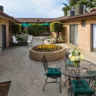 A peaceful courtyard with a central flower bed, surrounded by outdoor seating and tables.