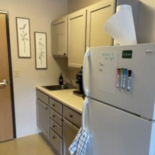 A compact kitchen with a refrigerator, cabinets, and a small sink area.