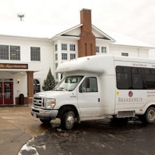 A white shuttle bus parked outside a residential facility during winter.