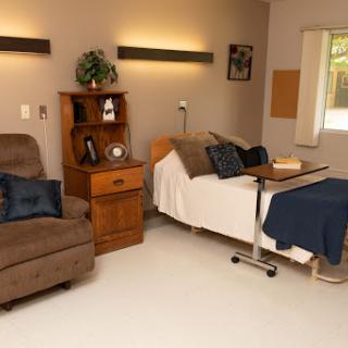 A cozy hospital room designed for patient comfort, featuring a bed, recliner, and essential medical furnishings.