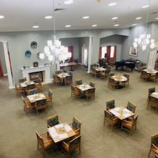 A spacious dining room with neatly arranged tables and chairs, modern lighting fixtures, and a cozy fireplace.
