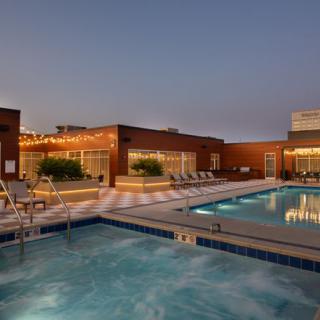 Rooftop swimming pool at dusk with city views.
