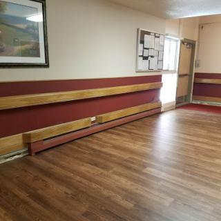 A spacious and well-lit indoor room featuring wooden flooring and decorative wall accents.