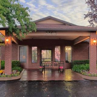 An inviting entrance to a brick building, featuring a covered walkway and well-maintained landscaping.