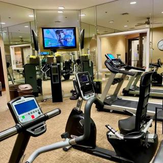 A well-equipped gym with treadmills, a stationary bike, and a television.